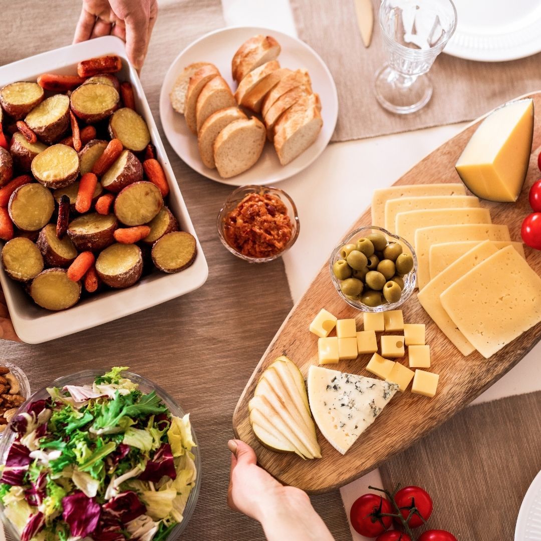 Photo of assorted foods on a table with hands serving family style