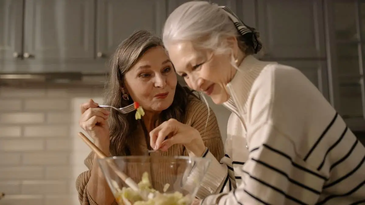 Photo of two older women sharing a salad together.