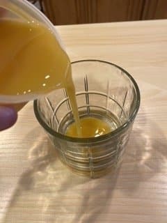 Mildly thick orange juice being poured into a clear glass.