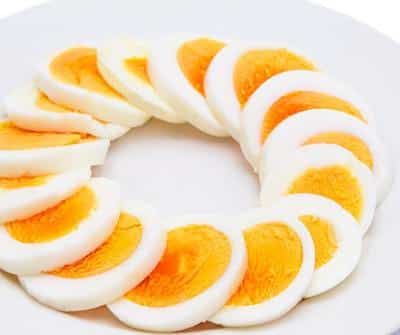 Sliced boiled eggs arranged in a circle on a white plate.