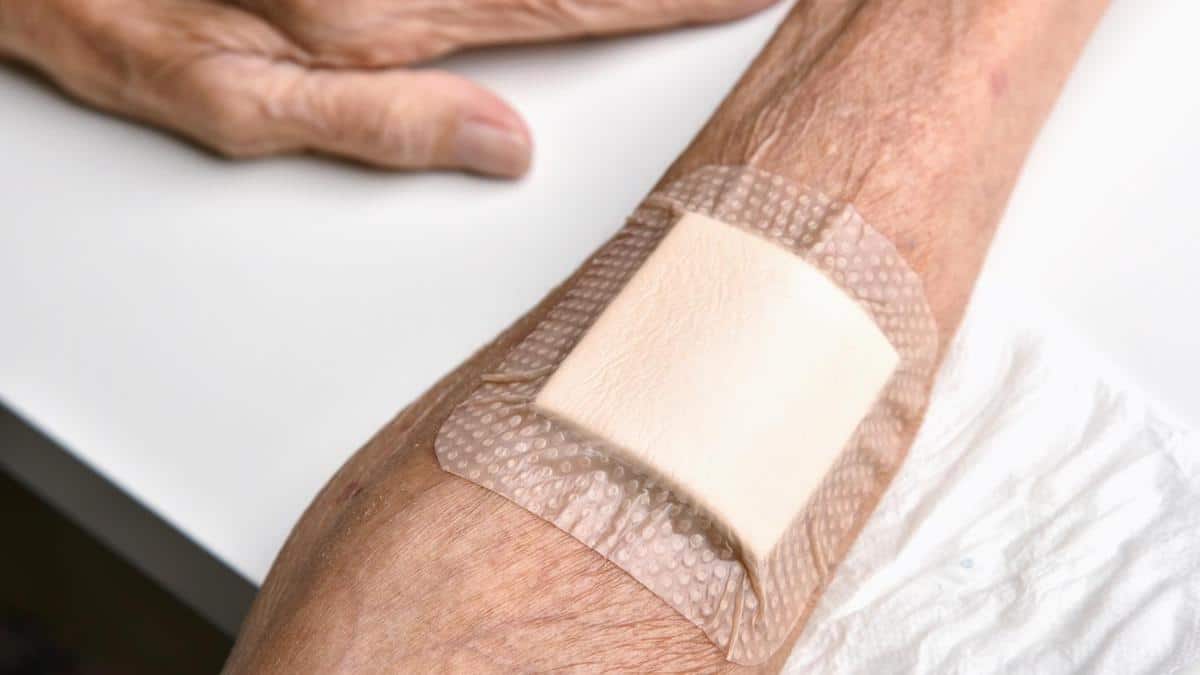 Elderly arm with square bandage on it.