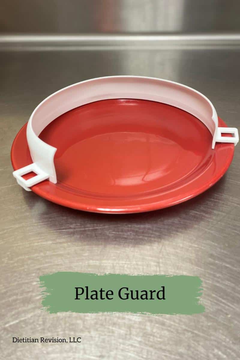 White plate guard attached to red plate sitting on stainless steel surface. 