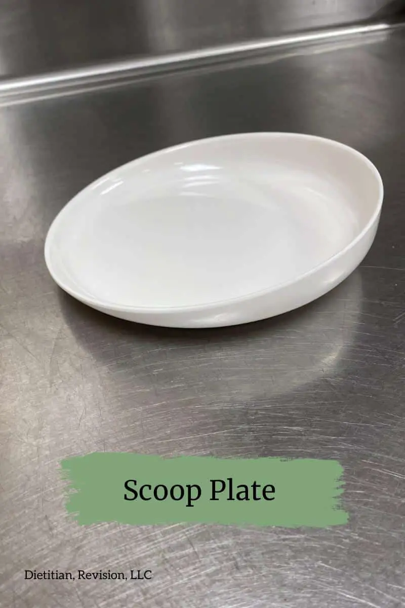 White scoop plate sitting on stainless steel table. 