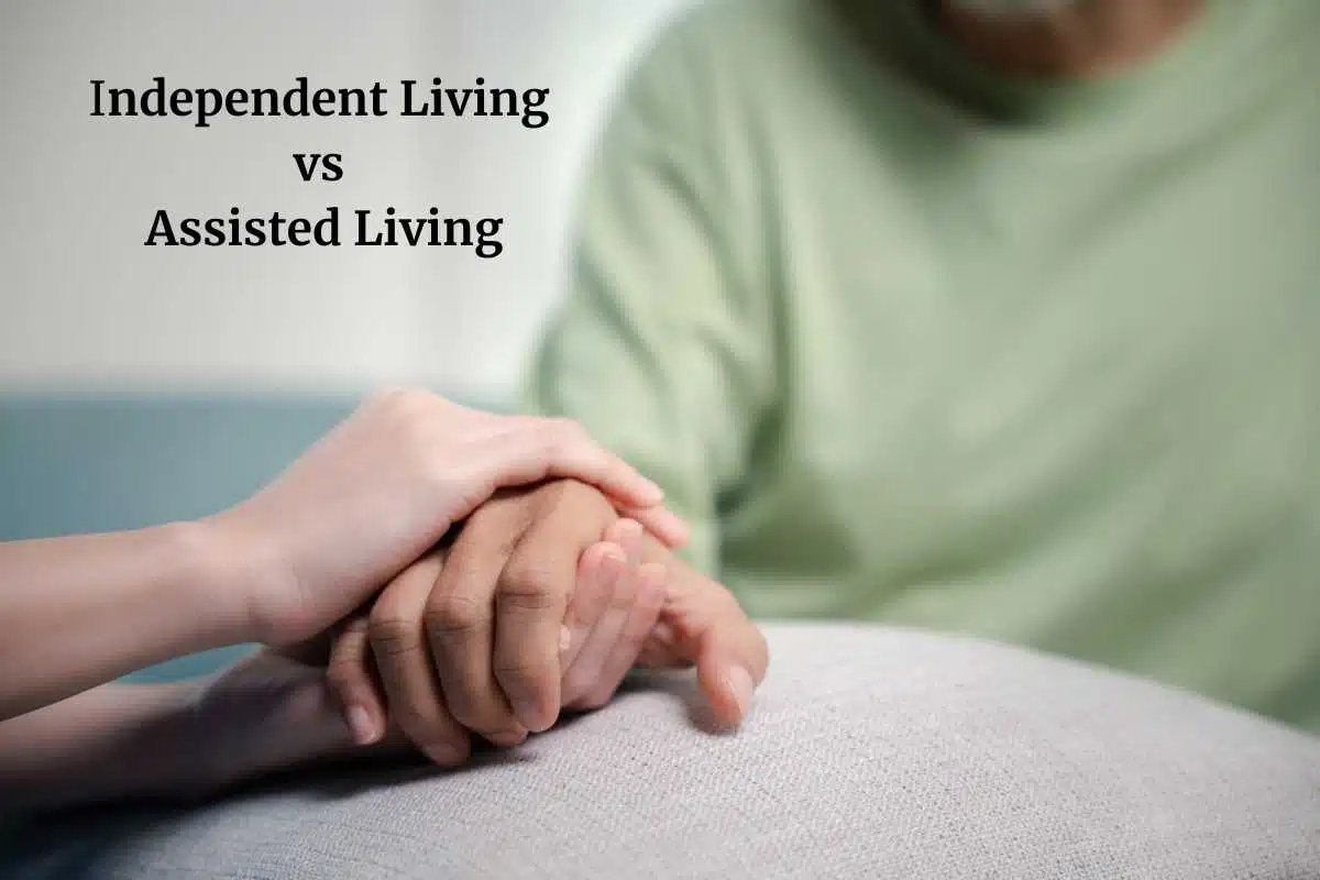 Image of older adult in green sweater hold hands with a younger person at a white table with black text independent living vs assisted living.