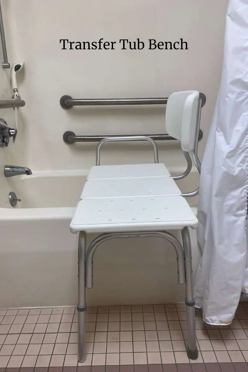 Transfer tube bench in white bathtub with silver grab bars.